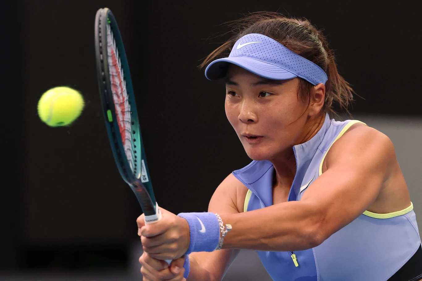 Tenisistka w sportowym stroju koncentruje się na odbiciu lecącej piłki tenisowej rakietą podczas meczu.