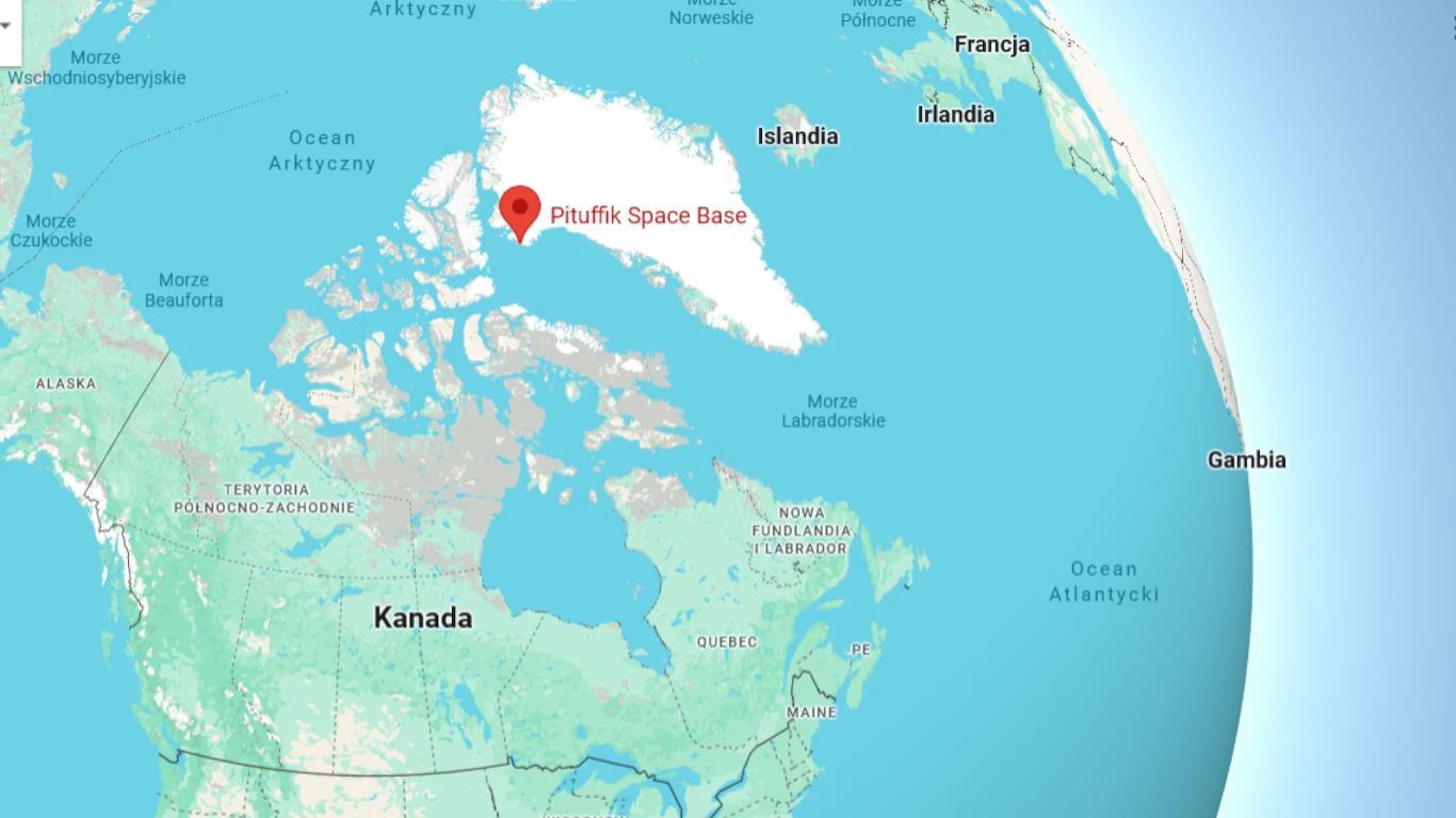 Mapa północnej części globu z oznaczoną lokalizacją bazy Puutfiik Space Base na Grenlandii, z widocznymi fragmentami Kanady, Islandii, Francji i Gambii oraz zaznaczonymi ważniejszymi miastami i granicami państw.