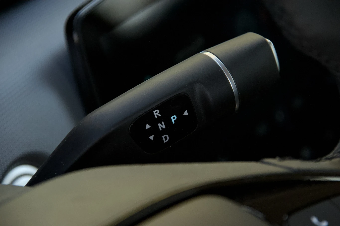 Dźwignia zmiany biegów w samochodzie, ustawiona w pozycji parkingowej P, wyraźnie widoczne oznaczenia R, N, D, otoczenie wnętrza auta.