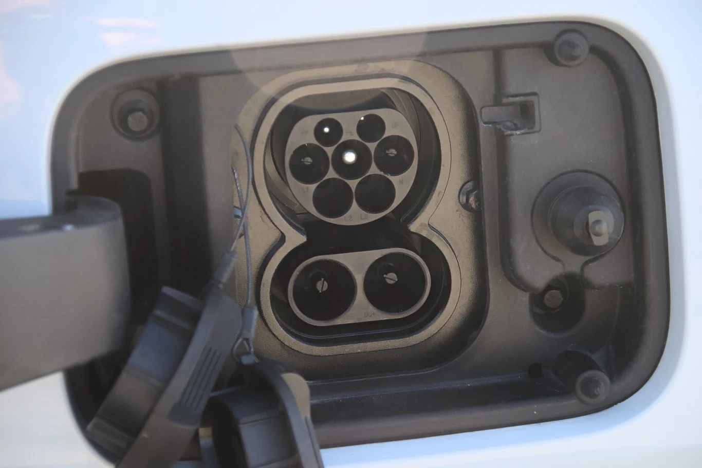 Gniazdo ładowania samochodu elektrycznego z widocznymi stykami oraz uchyloną osłoną portu.