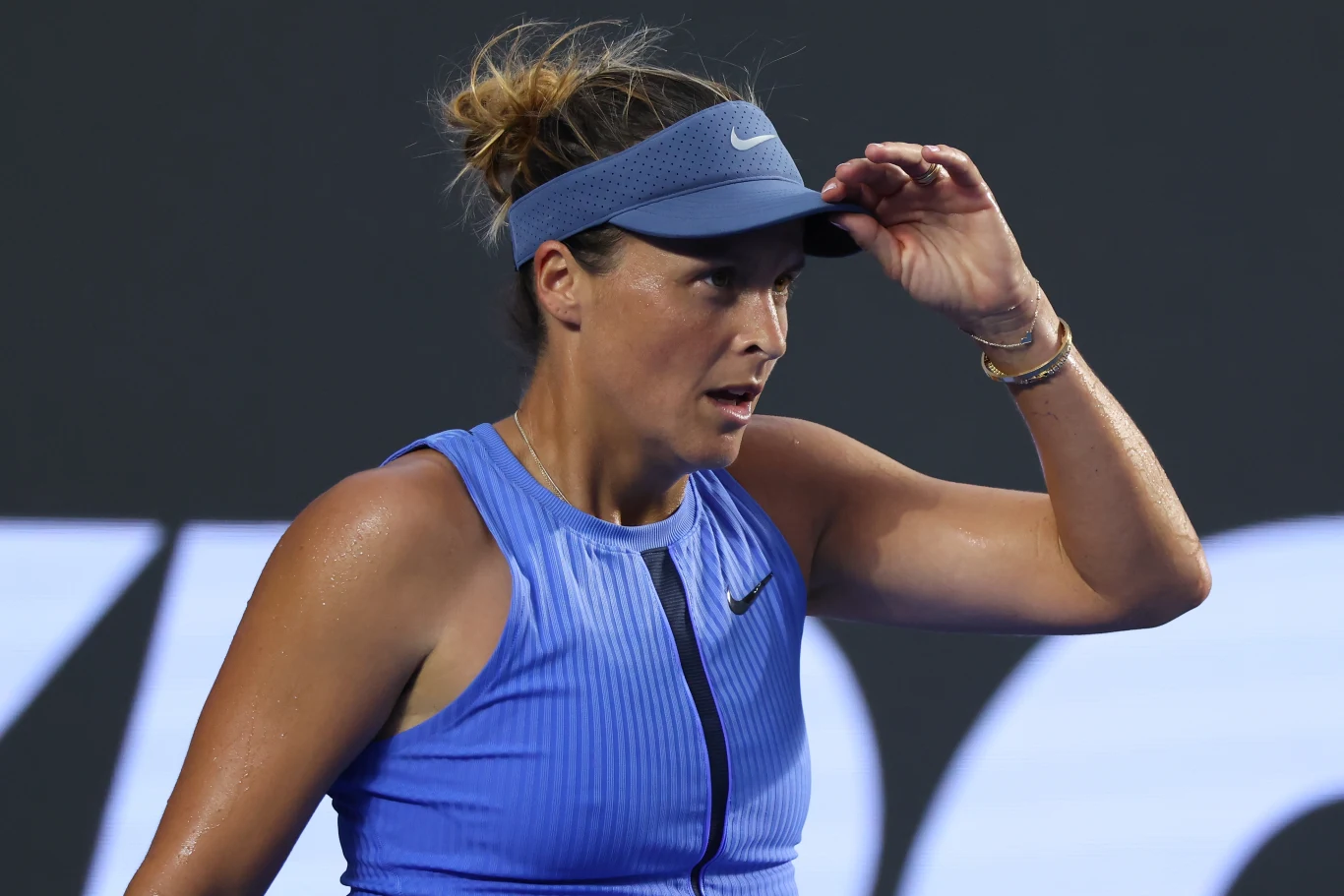 Tatjana Maria Tenisistka w niebieskim stroju sportowym i opasce na głowie poprawia nakrycie głowy podczas rozgrywki na korcie tenisowym.