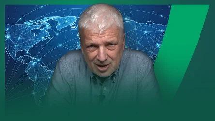 Starszy mężczyzna z siwymi włosami, ubrany w niebieską koszulę, na tle cyfrowej mapy świata z oznaczonymi połączeniami sieciowymi, sugerującej globalną komunikację lub technologię.