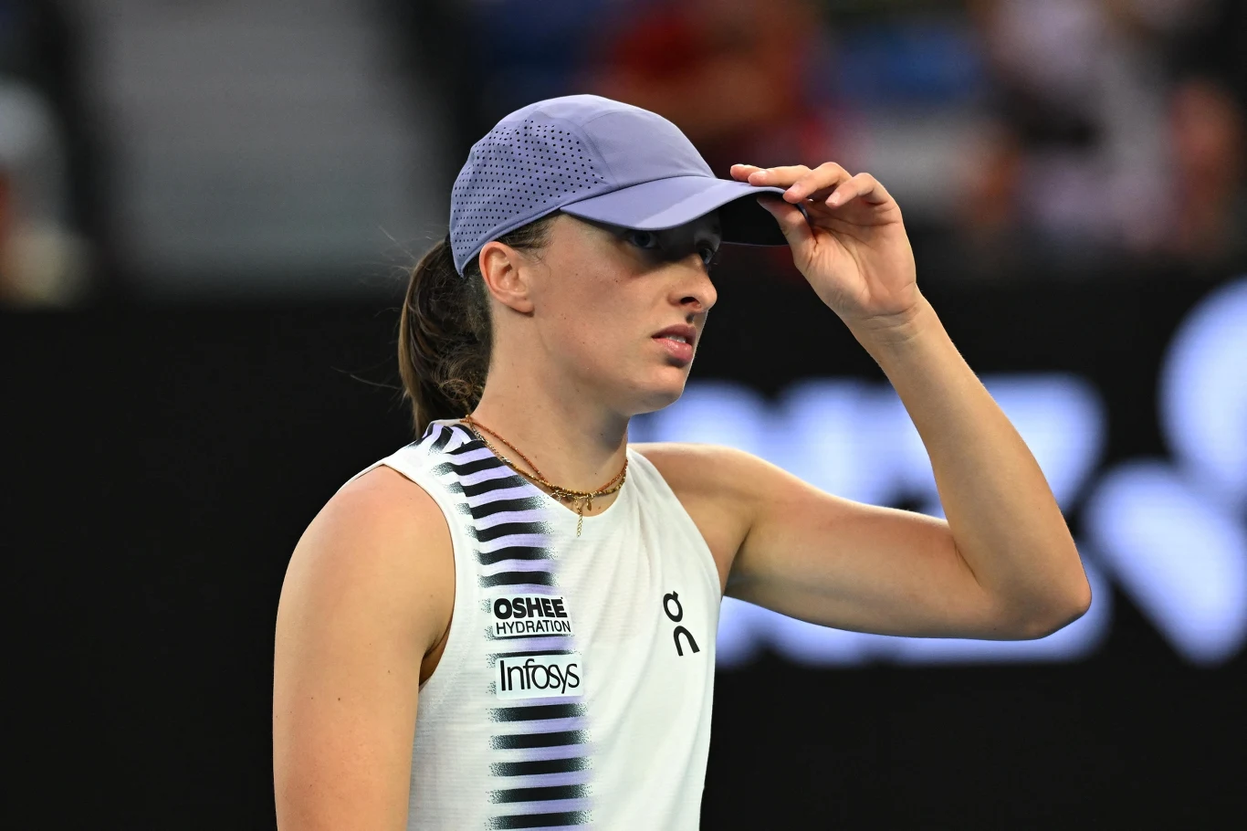 Iga Świątek Tenisistka w sportowym stroju i czapce z daszkiem poprawia nakrycie głowy podczas meczu na korcie tenisowym.