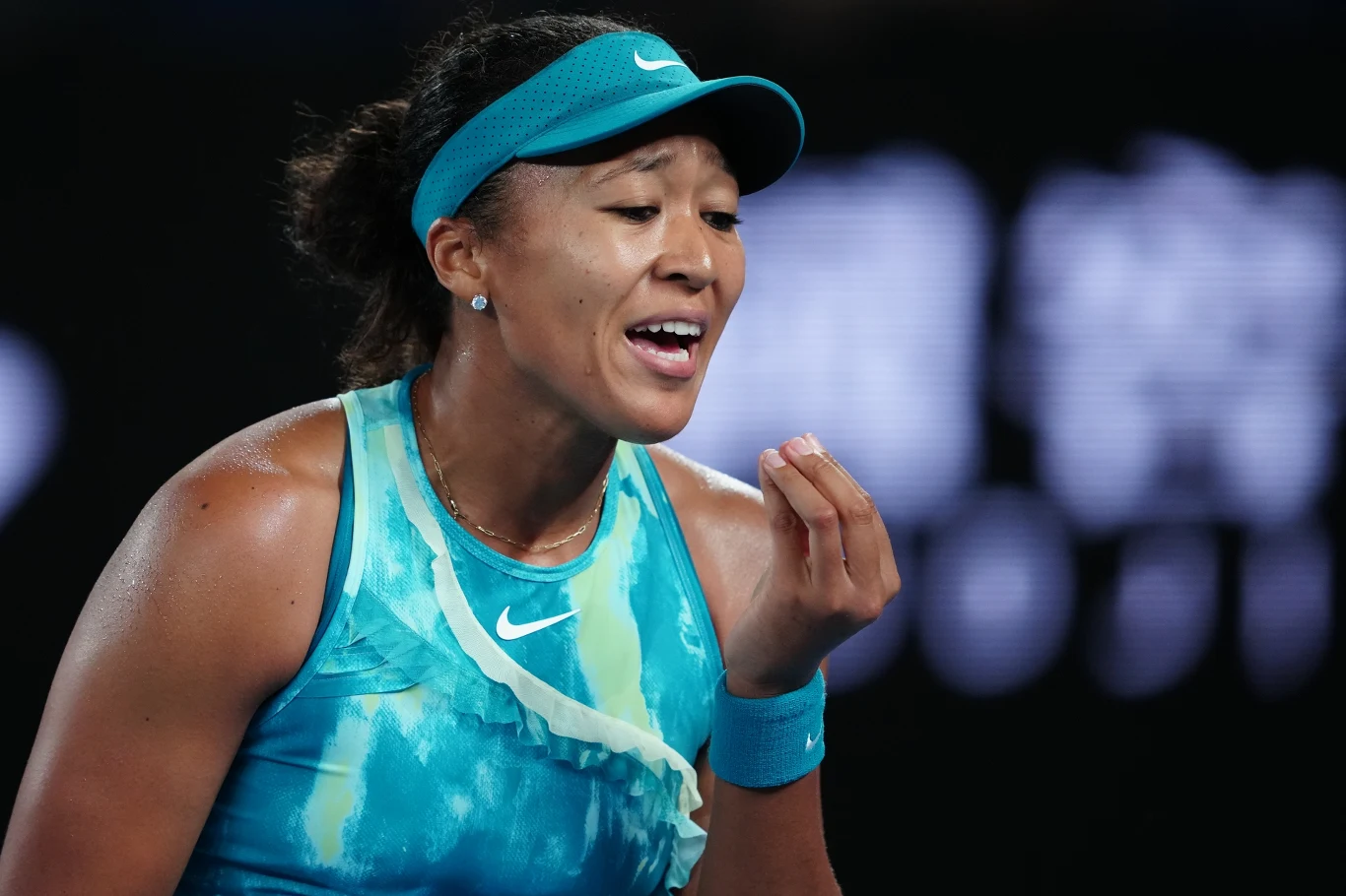 Naomi Osaka nerwowo przywitała się z Australian Open Tenisistka w niebieskim stroju sportowym energicznie gestykuluje podczas meczu na korcie, wyrażając silne emocje.