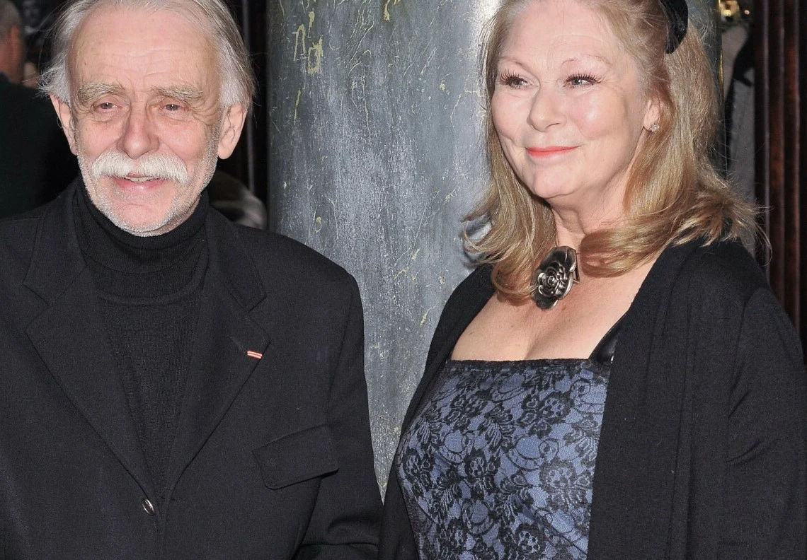 Stefan Szmidt i Alicja Jachiewicz Starszy mężczyzna w czarnym golfie i marynarce stoi obok kobiety uśmiechającej się, ubranej w elegancką suknię z koronką i ozdobnym naszyjnikiem, oboje prezentują się oficjalnie i pogodnie.