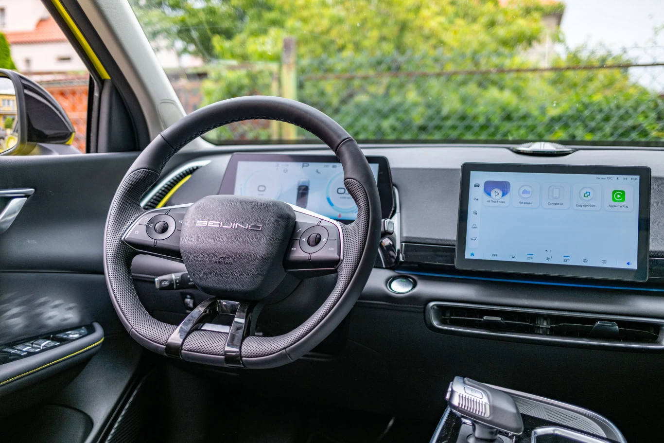 Nowoczesne wnętrze samochodu elektrycznego z cyfrowym kokpitem, skórzaną kierownicą, dużym wyświetlaczem centralnym oraz minimalistycznym panelem sterowania.