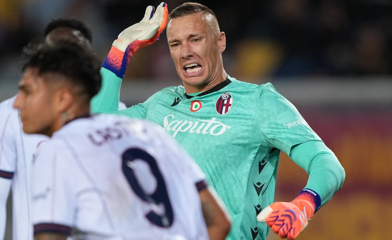 Łukasz Skorupski Bramkarz w zielonym stroju drużyny Bologna energicznie reaguje podczas rozgrywki, w tle widoczny inny zawodnik z numerem 9 na koszulce.