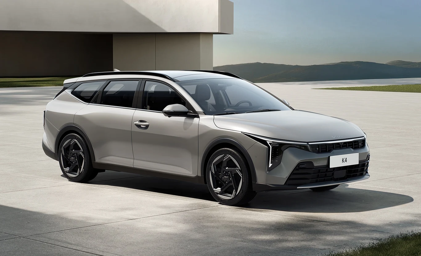 Nowoczesny srebrny samochód kombi zaparkowany przed minimalistycznym budynkiem, z widokiem na spokojny krajobraz górski w tle. Designerskie felgi i futurystyczna linia reflektorów podkreślają jego dynamiczny charakter.