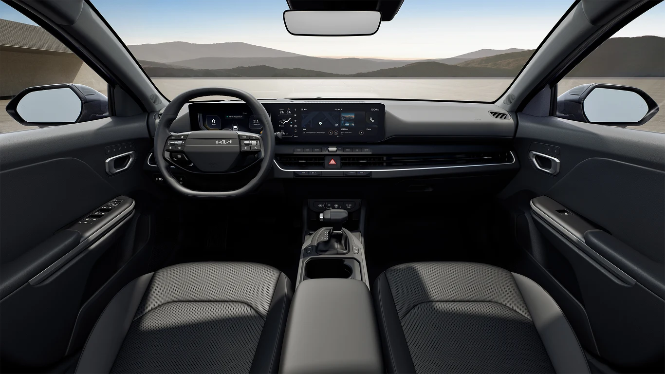 Nowoczesna deska rozdzielcza samochodu z dużym ekranem, elektronicznym panelem sterowania oraz dwukolorową, skórzaną tapicerką siedzeń. Przednia szyba ukazuje górzysty krajobraz na zewnątrz.