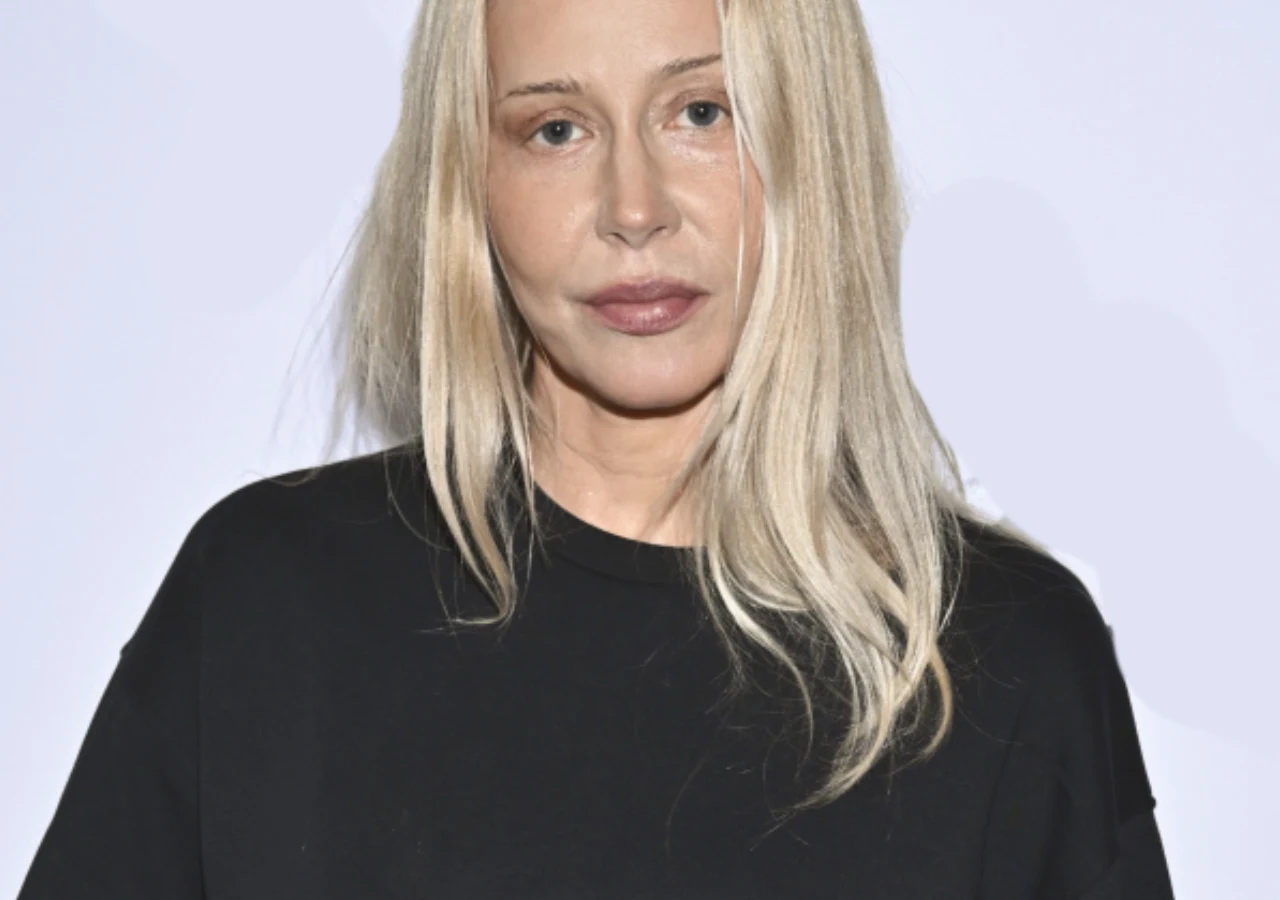 Katarzyna Warnke Kobieta o jasnych, długich włosach ubrana w czarną bluzę na tle jasnej, neutralnej ściany, patrząca prosto w obiektyw z naturalnym wyrazem twarzy.