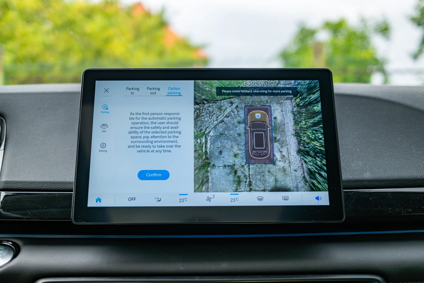 Wyświetlacz systemu multimedialnego samochodu z aktywną funkcją asysty parkowania przedstawiającą widok z kamery 360 stopni wraz z wizualizacją pojazdu podczas manewru.