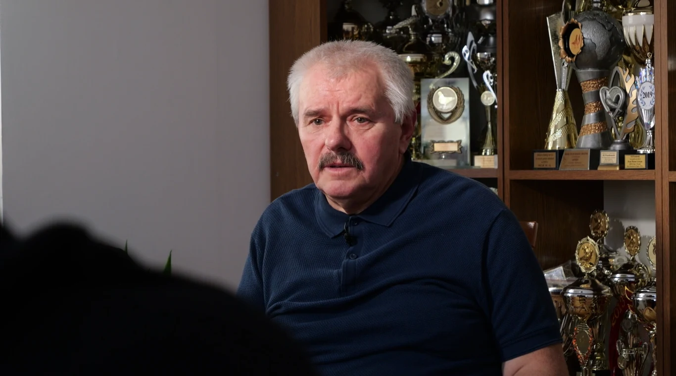Marian Pacuk ocalał w katastrofie budowlanej w Katowicach w 2006 r. Starszy mężczyzna z siwymi włosami i wąsami w granatowej koszuli, siedzący na tle regału wypełnionego licznymi pucharami i trofeami.