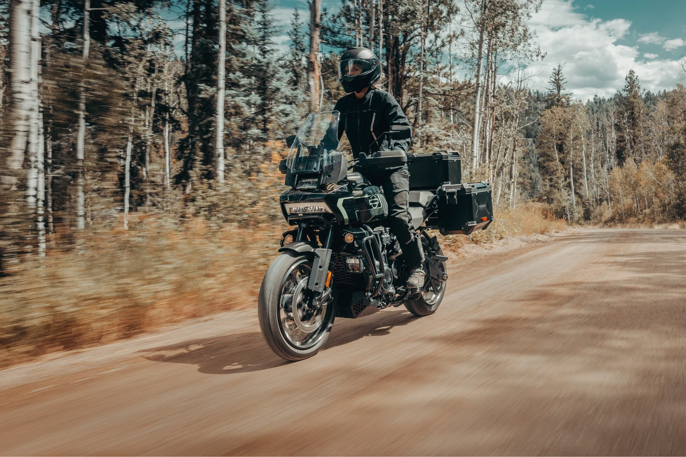Harley-Davidson zaprezentował 13 nowych modeli, które dołączyły do oferty motocykli na rok 2026. Motocyklista w pełnym stroju ochronnym jedzie motocyklem turystycznym po leśnej, nieutwardzonej drodze otoczonej drzewami.