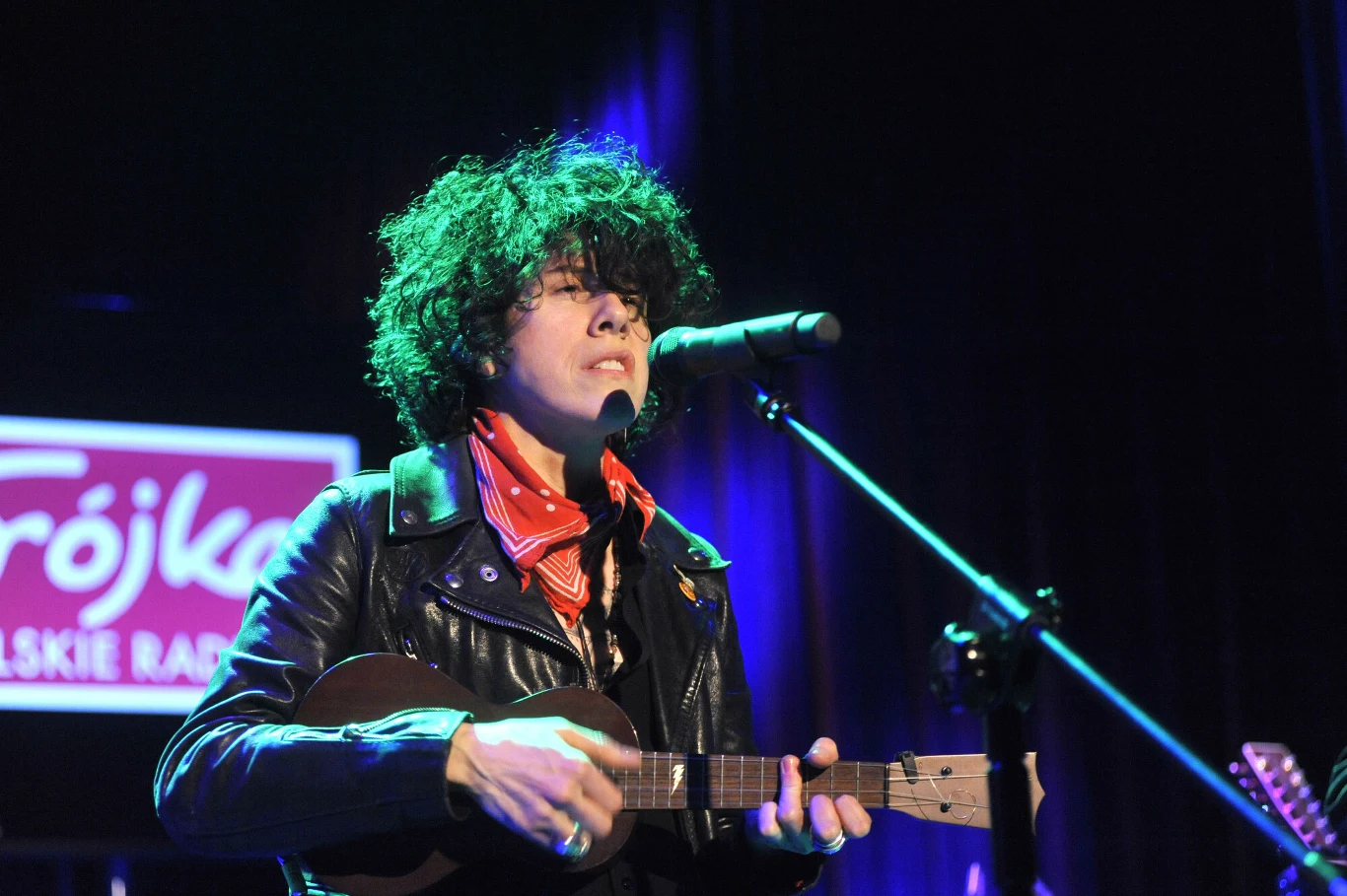 LP wystąpi na Open'er Festivalu 2026 Artystka z burzą kręconych włosów, ubrana w czarną skórzaną kurtkę i czerwoną bandanę, gra na ukulele i śpiewa do mikrofonu podczas koncertu, w tle widoczny neon z napisem Trójka Polskie Radio.