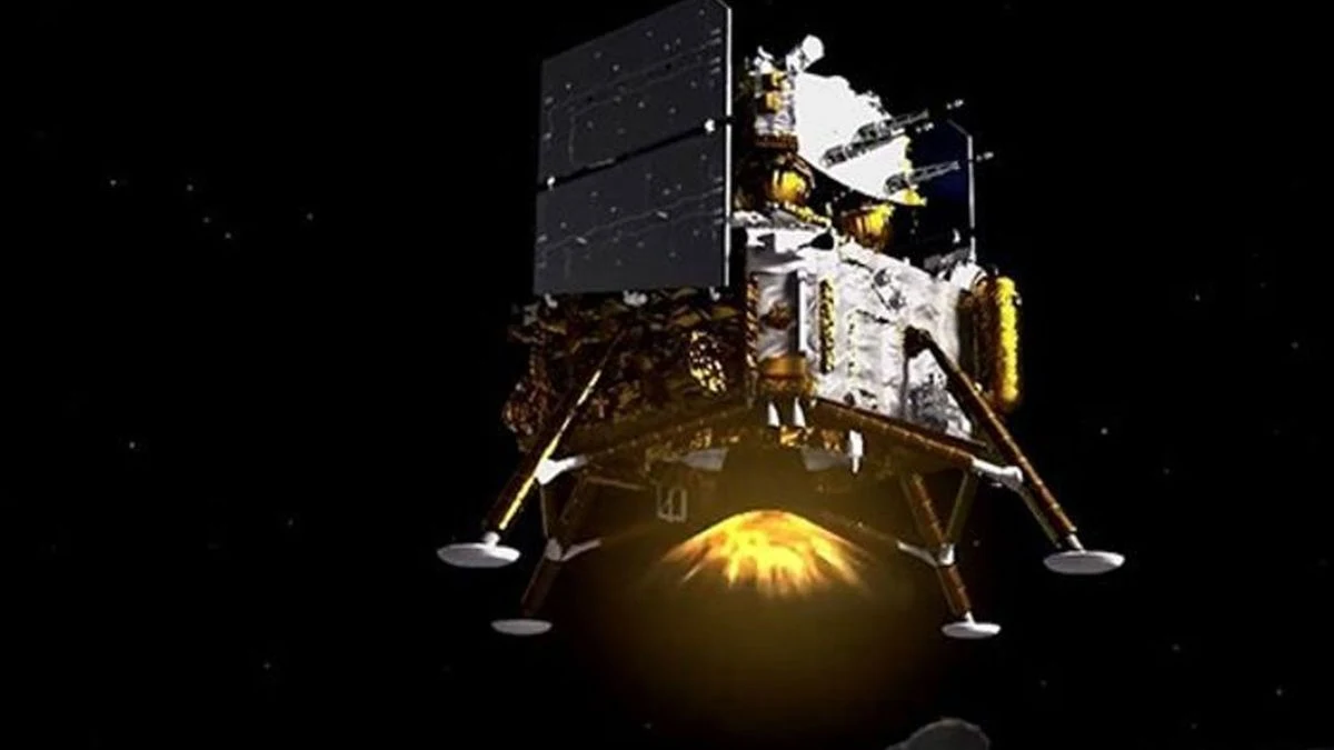 Lądownik kosmiczny z widocznym silnikiem podczas pracy, unoszący się w przestrzeni kosmicznej na tle czarnego nieba.