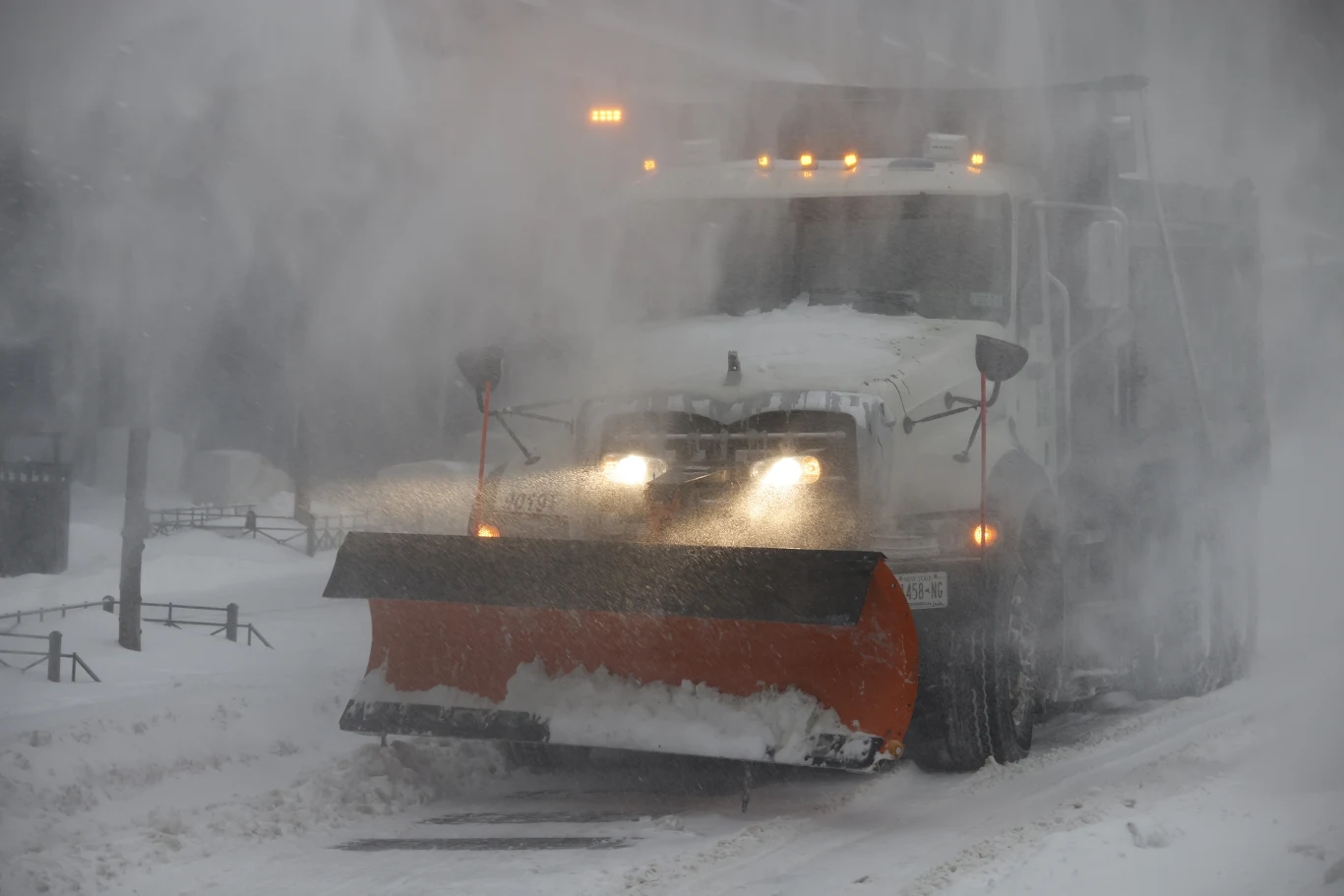 Atak zimy w Nowym Jorku. Z powodu śnieżyc i mrozów w ostatnich dniach zmarło tam co najmniej 10 osób Pług śnieżny usuwa śnieg z zaśnieżonej drogi podczas intensywnej śnieżycy, światła pojazdu przebijają się przez gęstą mgłę śnieżną.