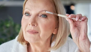 Dojrzała kobieta w białym szlafroku robi makijaż