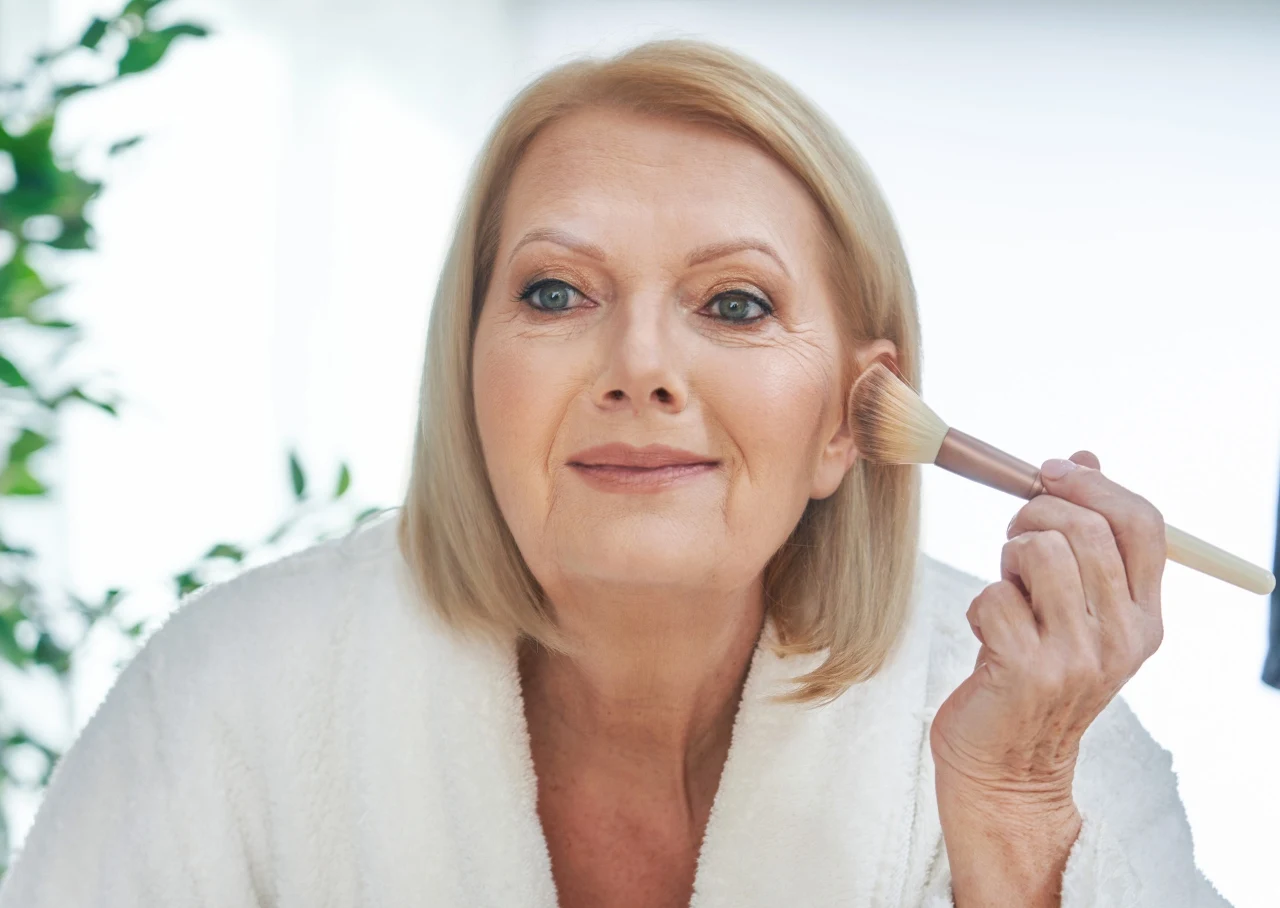 Dojrzała kobieta nakłada róż na kości policzkowe