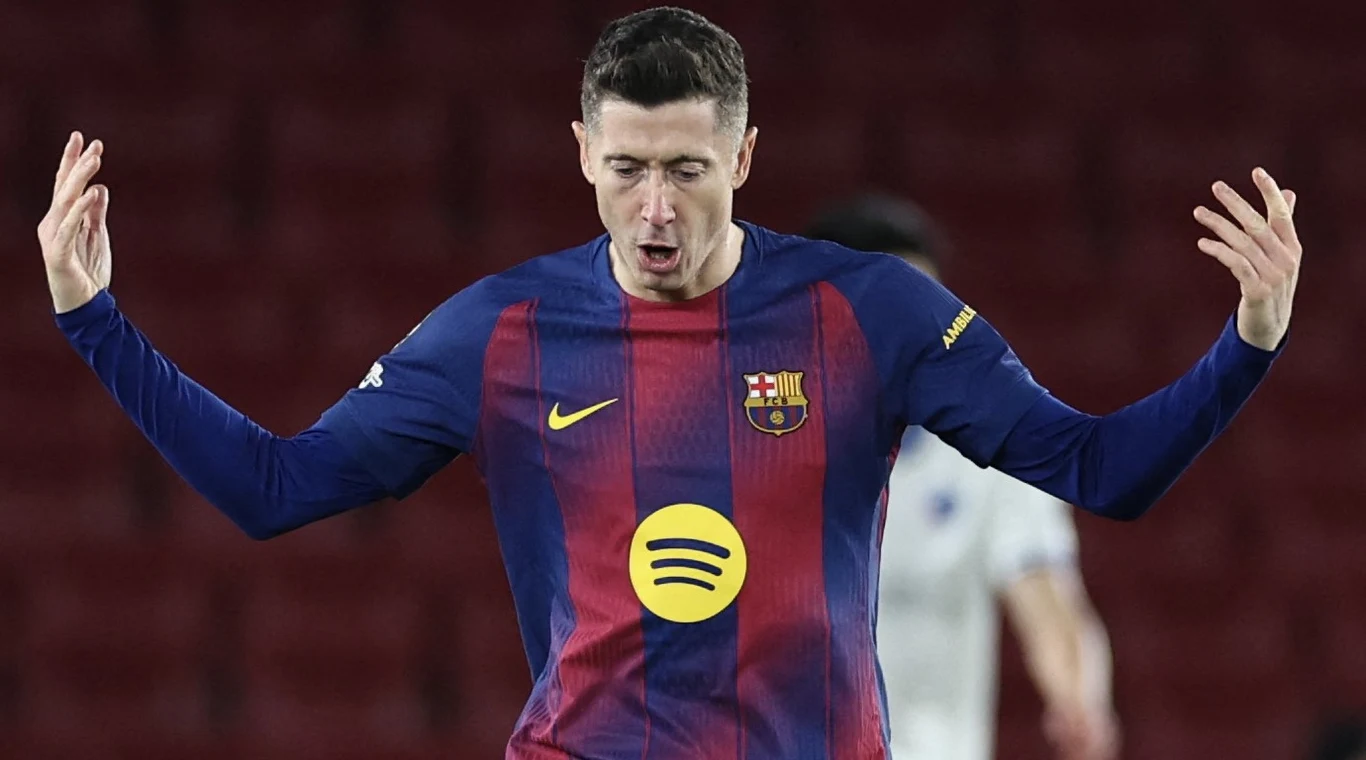 Robert Lewandowski Piłkarz w koszulce FC Barcelony z uniesionymi rękami na tle rozmytego stadionu, wyrażający silne emocje w trakcie meczu.
