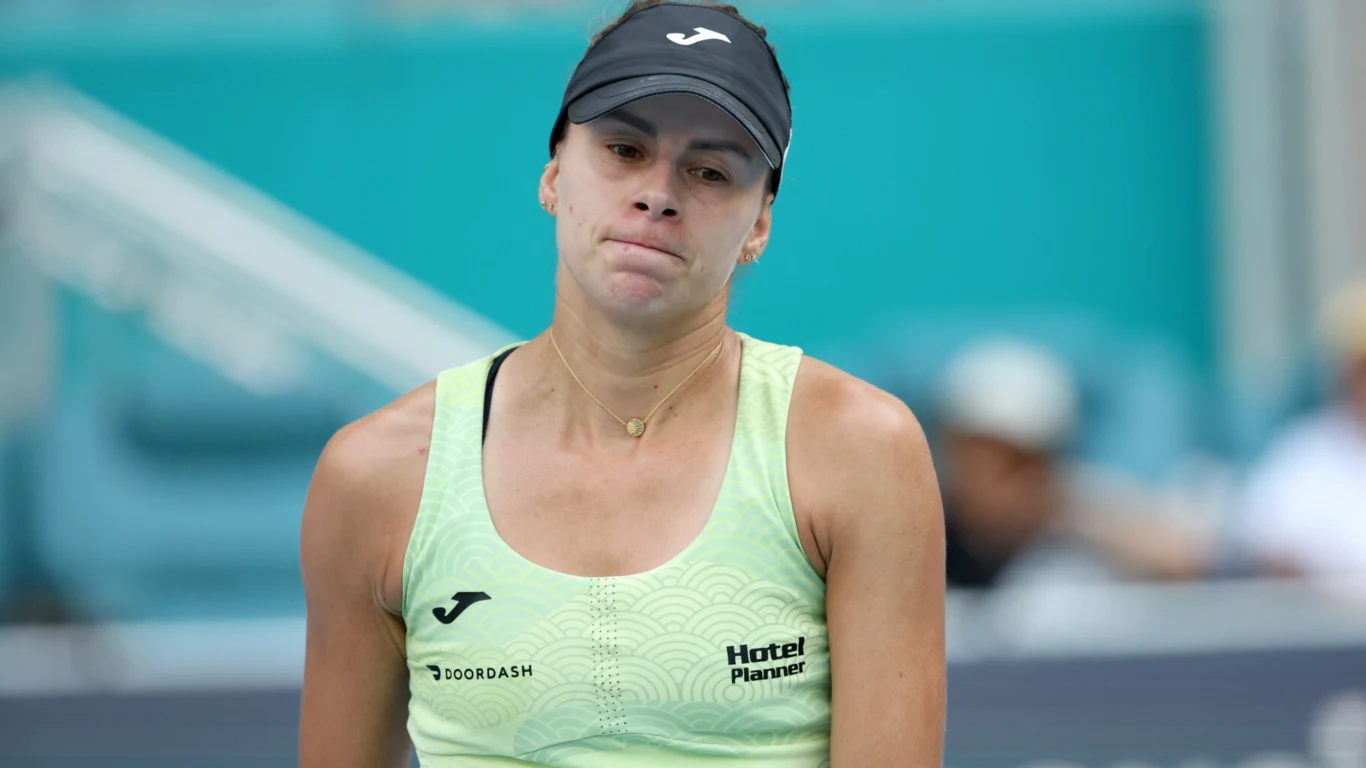 Magda Linette Tenisistka w jasnozielonym stroju sportowym oraz czapce z daszkiem, wyrażająca emocje po zakończonej akcji na korcie tenisowym, rozmyte tło areny sportowej.