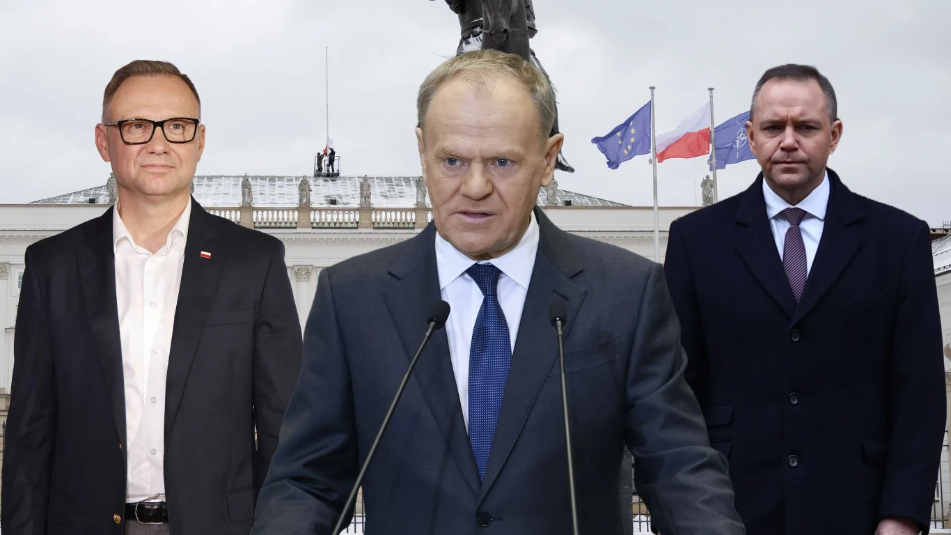 Premier publicznie upomina prezydentów. "Nie jest waszą rolą" Trzech mężczyzn w garniturach stoi na tle budynku z flagami Polski i Unii Europejskiej. Jeden z nich przemawia do mikrofonu, pozostali stoją po jego bokach. W tle widoczny fragment pomnika.