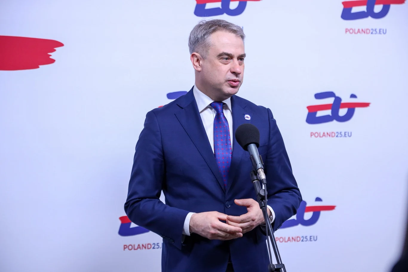 Służby zatrzymały mężczyznę, który groził wicepremierowi. Na zdjęciu Krzysztof Gawkowski Mężczyzna w garniturze przemawia do mikrofonu na tle ścianki z logo i napisem POLAND25.EU.