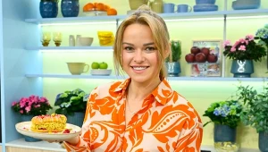 Karolina Stolarska-Bigos z talerzem, na którym leży eklerka