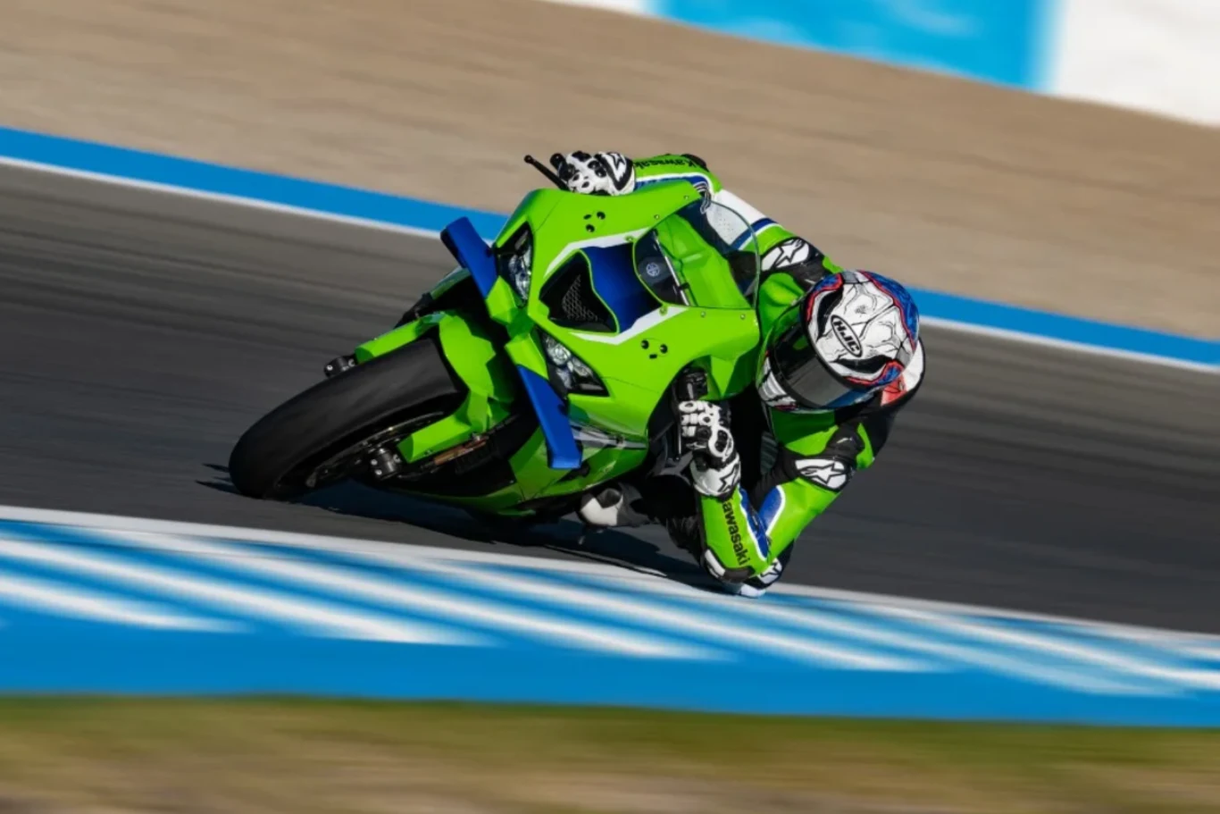 Torowa broń została jeszcze bardziej dopracowana. Oto nowy ZX-10R na rok 2026. Motocyklista ubrany w zielony kombinezon i kask pochyla się na zakręcie toru wyścigowego, jadąc na zielonym motocyklu sportowym. Tło rozmazane, podkreślając prędkość i dynamikę jazdy.