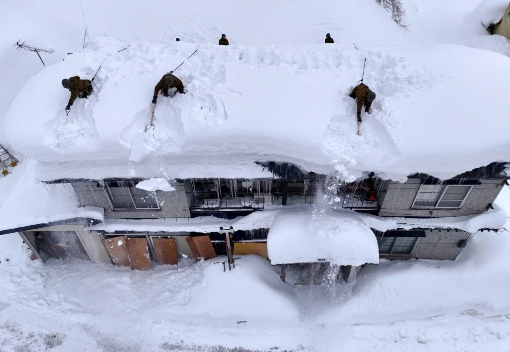 Żołnierze Japońskich Sił Samoobrony usuwają zaspy śniegu z dachu posesji w Aomori
