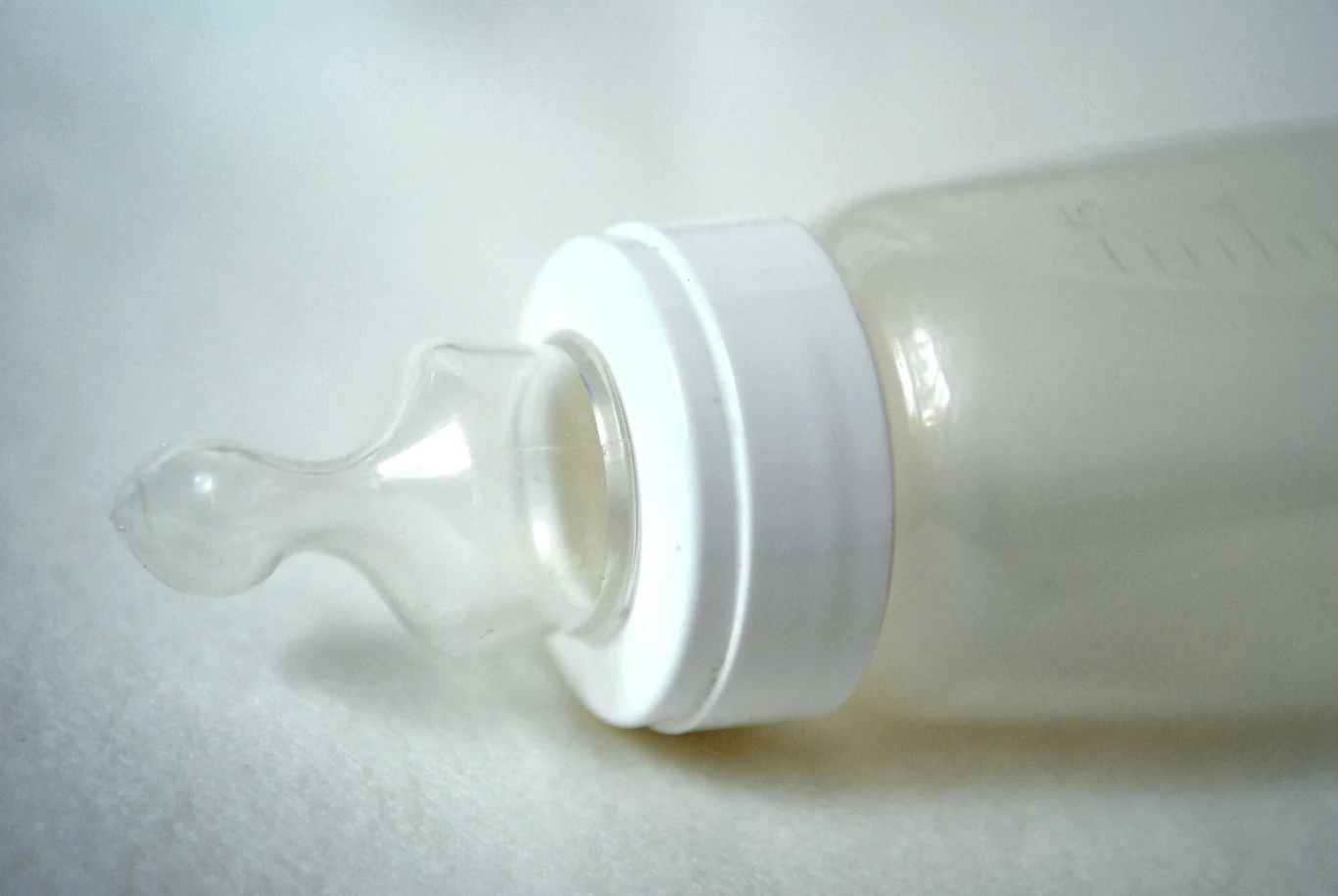 GIS poinformował o wycofaniu ze sprzedaży niektórych partii mleka dla niemowląt Butelka do karmienia niemowląt z przezroczystym smoczkiem i białą nakrętką leżąca na jasnej powierzchni.