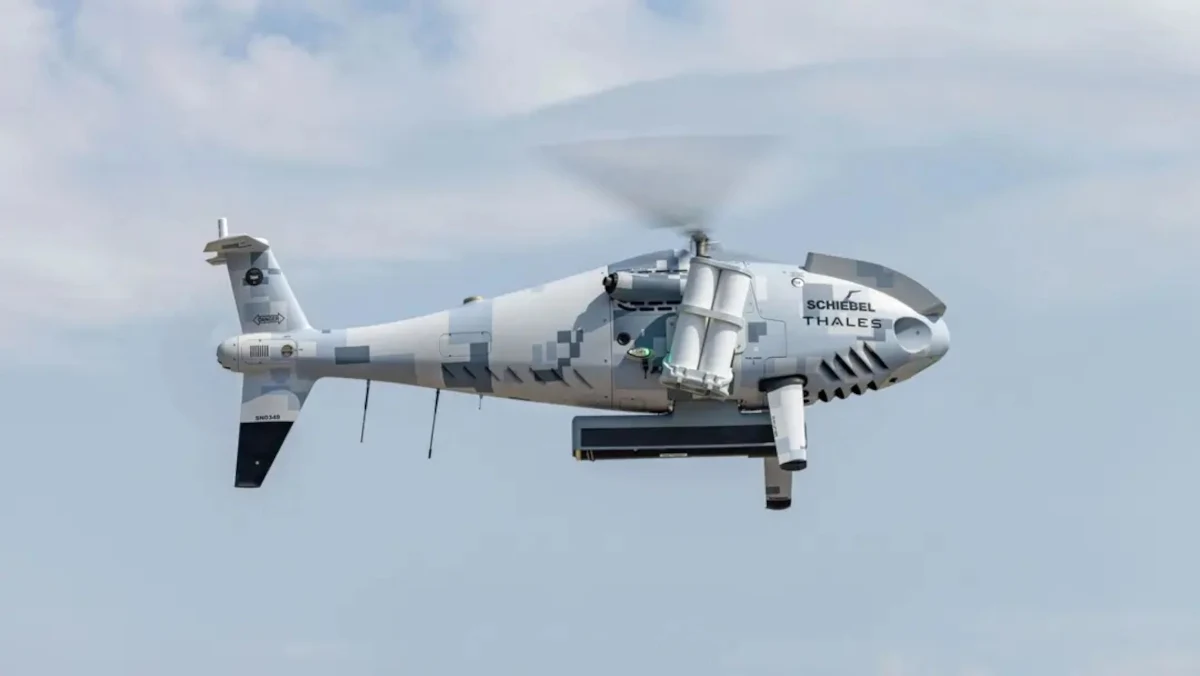 Austria ma bata na rosyjskie drony Shahed. Stworzono bezzałogowy śmigłowiec. Bezzałogowy śmigłowiec wojskowy w locie na tle nieba, widoczne oznaczenia producenta oraz wyposażenie technologiczne pod kadłubem.