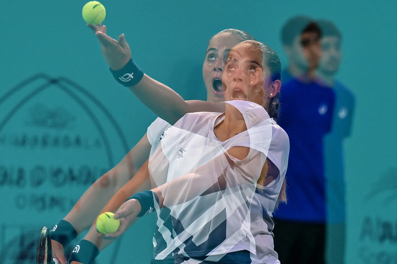 Tenisistka wykonująca serwis podczas meczu, widoczny efekt nałożenia dwóch ekspozycji ukazujący ruch ręki oraz piłki tenisowej, na dalszym planie sędzia i rozmyte logo turnieju.