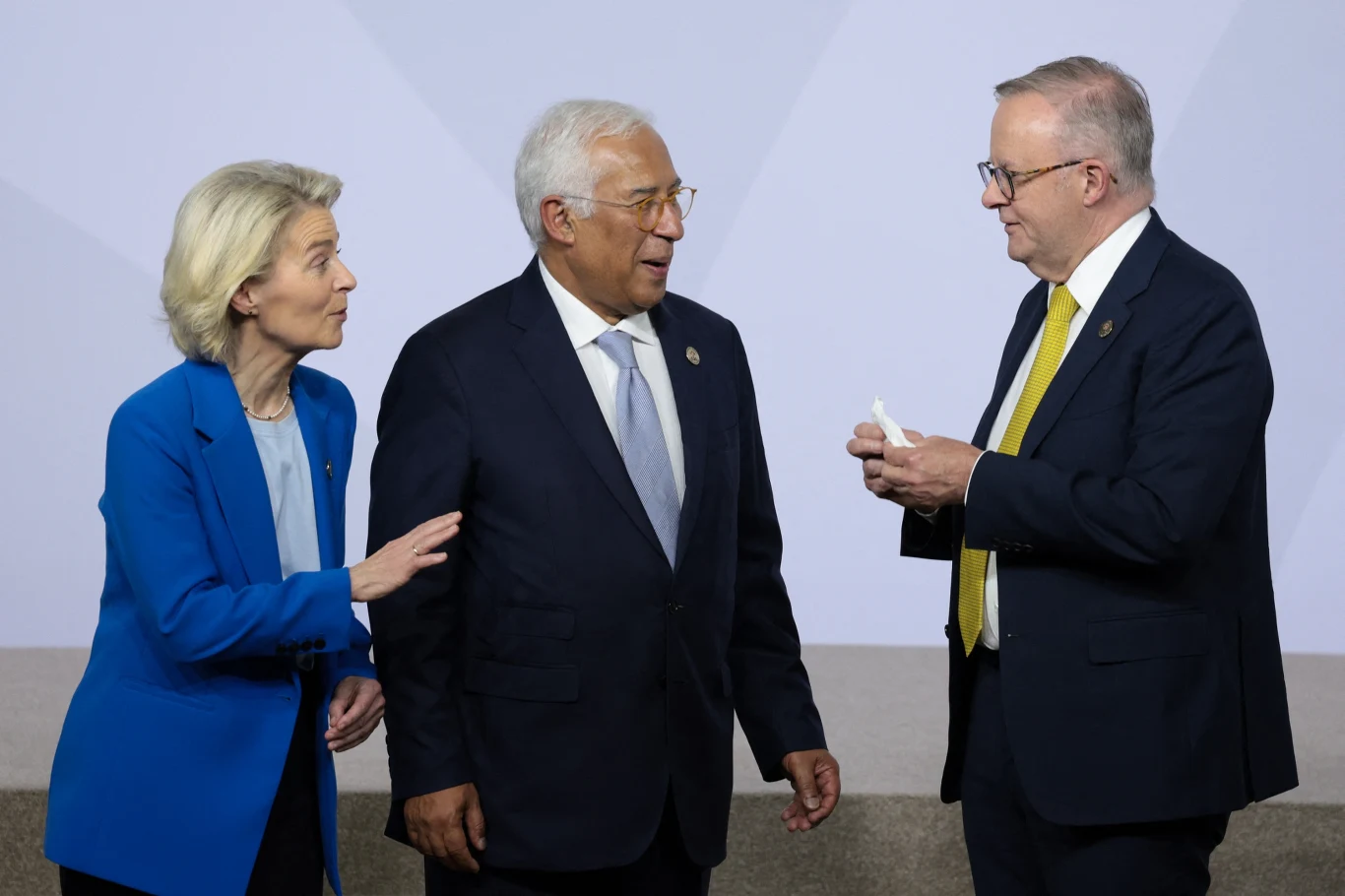 UE szykuje się do podpisania umowy handlowej z Australią. Na zdj. od lewej: szefowa KE Ursula von der Leyen szef rady europejskiej Antonio Costa i premier Australii Anthony Albanese, Trzy osoby ubrane w formalne stroje rozmawiają ze sobą, jedna z nich trzyma kartkę lub dokument w ręku, wszyscy wyglądają na skupionych i zaangażowanych w rozmowę, tło w jasnych kolorach bez dodatkowych elementów.