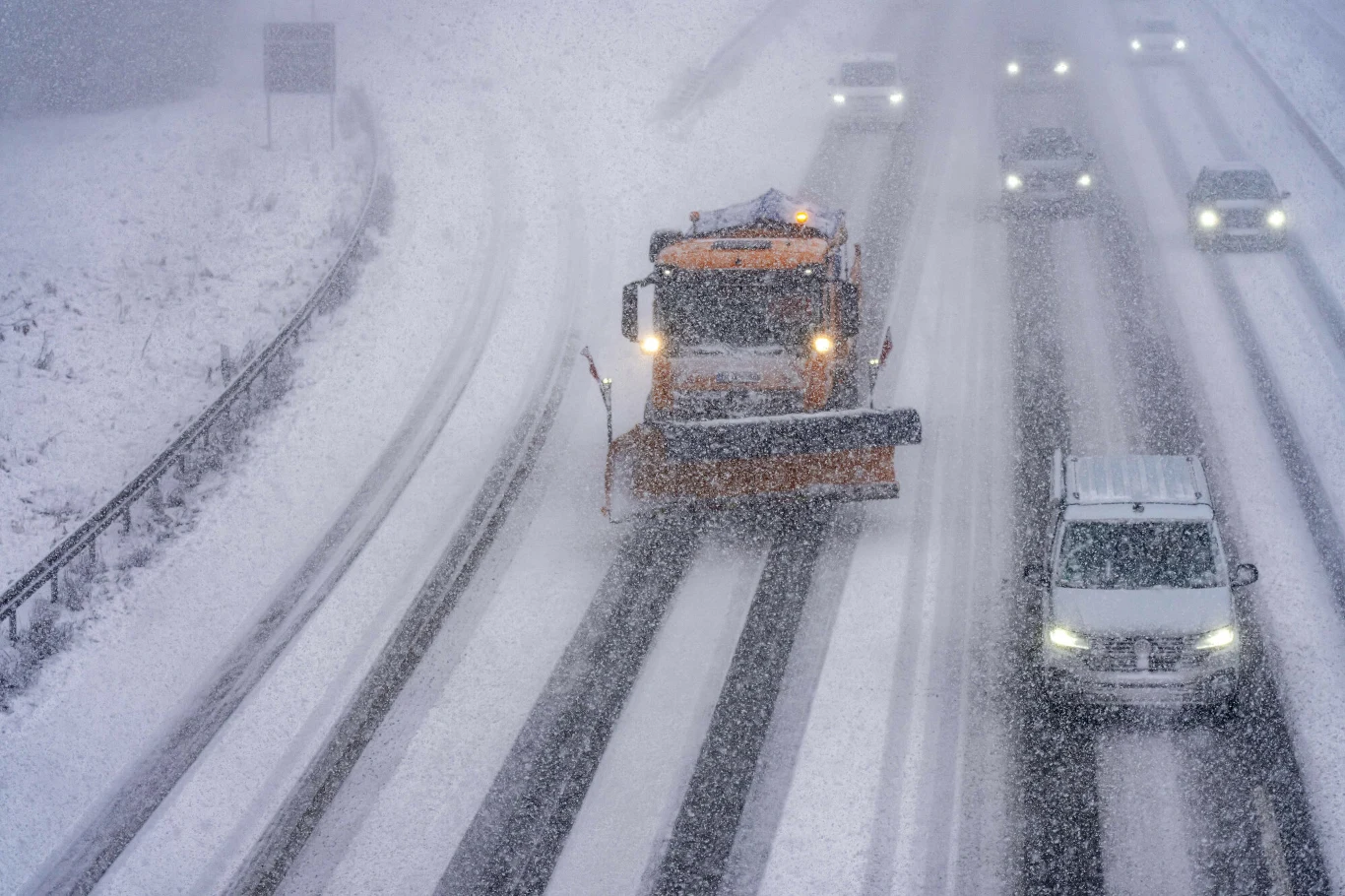Berlin jest oblodzony podobnie jak wiele innych miast Europy Pług śnieżny odśnieża zaśnieżoną autostradę, wokół poruszają się samochody w trudnych warunkach pogodowych, ograniczona widoczność spowodowana intensywnymi opadami śniegu.