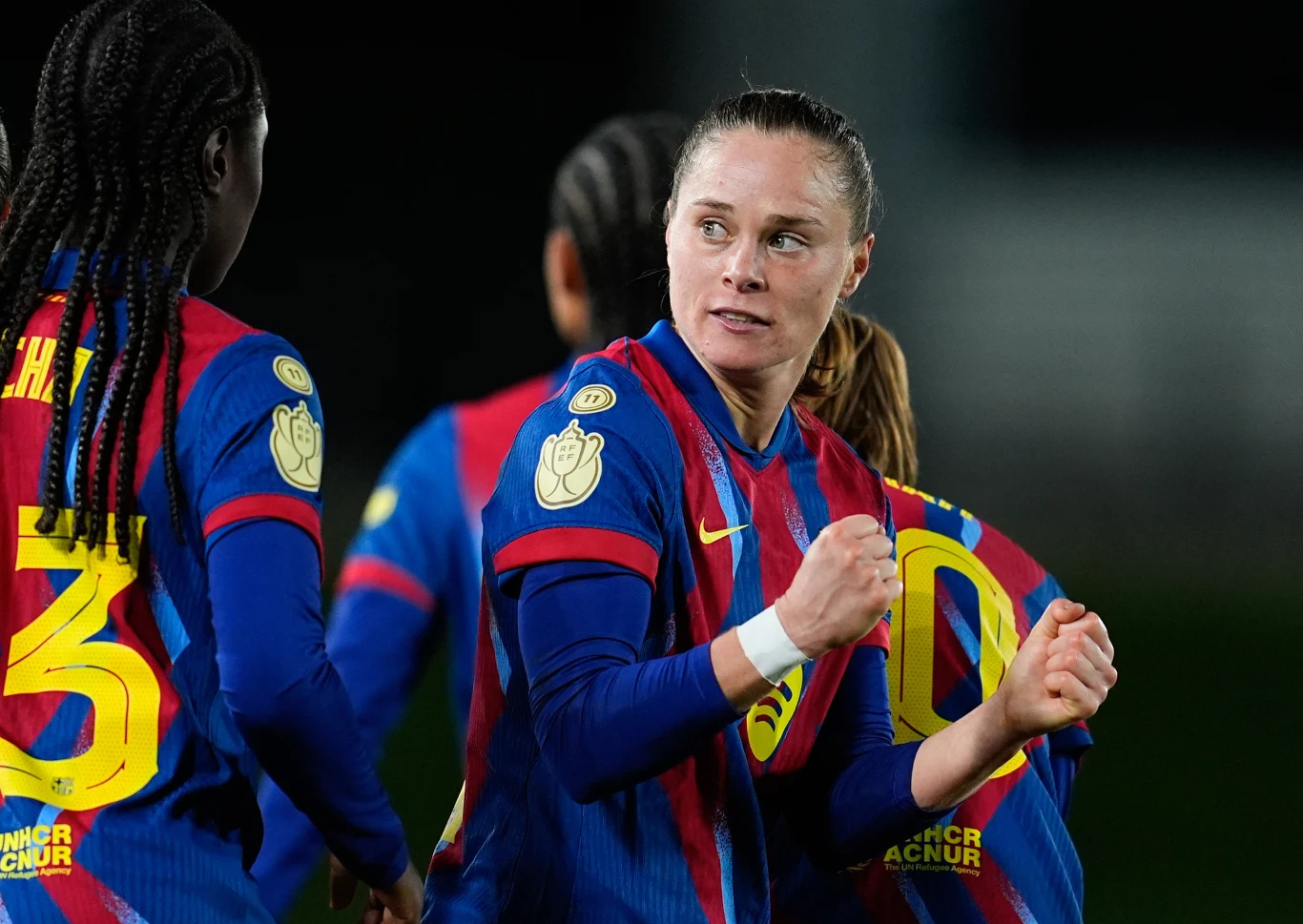 Ewa Pajor celebrująca bramkę przeciwko Realowi Madryt Zawodniczki drużyny FC Barcelona w koszulkach klubowych, jedna z piłkarek jest na pierwszym planie, unosi zaciśnięte pięści w geście radości lub determinacji, w tle widoczne są koleżanki z zespołu.