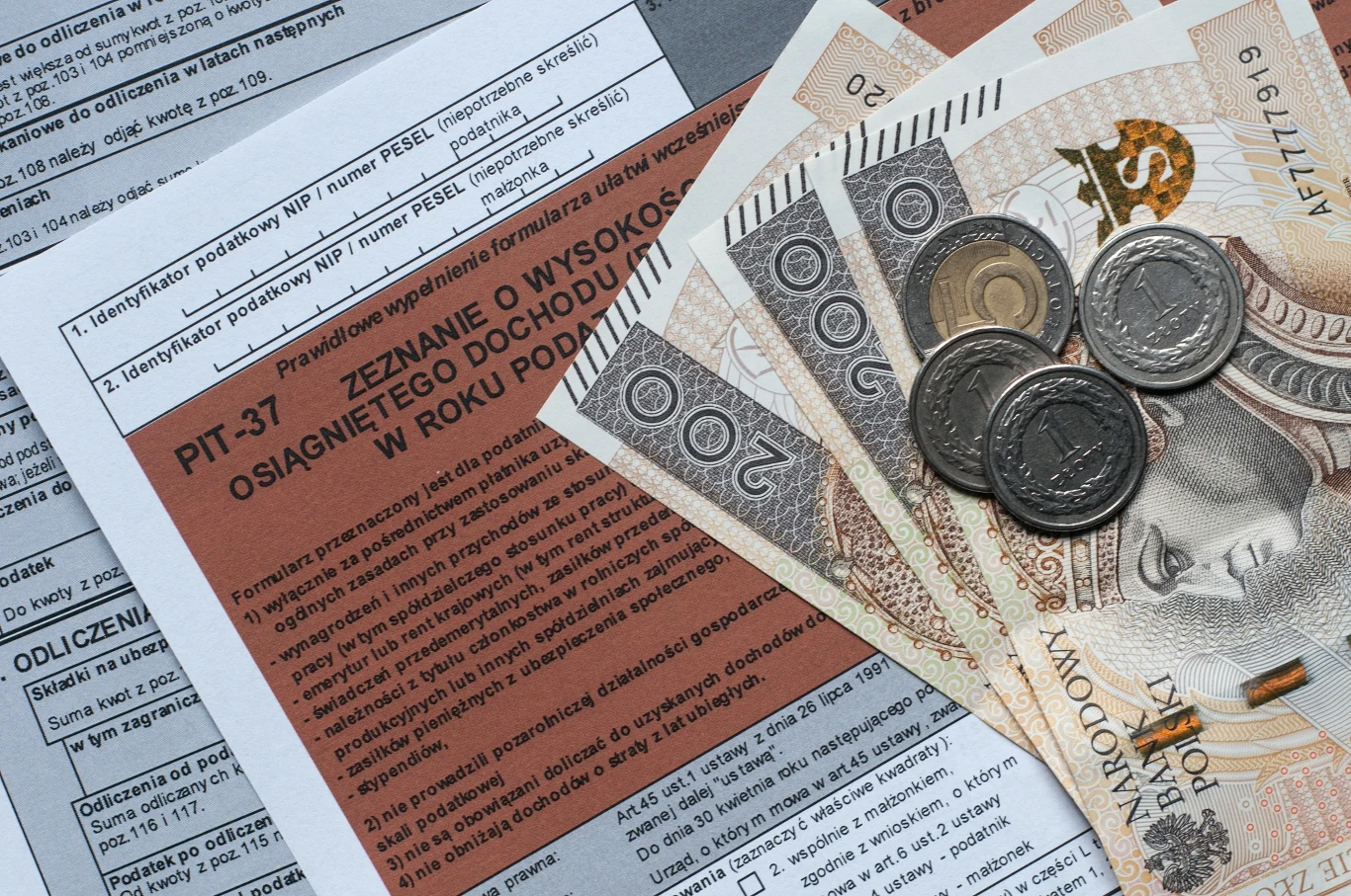 Nawet 760 zł zwrotu podatku. Z jednej ulgi w PIT można skorzystać dwa razy. Formularz PIT-37 wypełniony danymi podatkowymi oraz polskie banknoty i monety ułożone na nim, symbolizujące rozliczenia podatkowe i kwestie finansowe.
