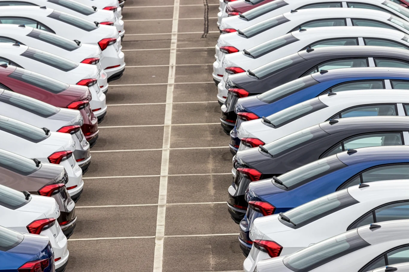Rok 2025 był rekordowy dla polskiej branży leasingowej Szeregowo ustawione nowe samochody osobowe różnych kolorów na parkingu, widoczne z perspektywy lotu ptaka. Auta są zaparkowane równolegle w dwóch rzędach, zajmując większość widocznej przestrzeni.