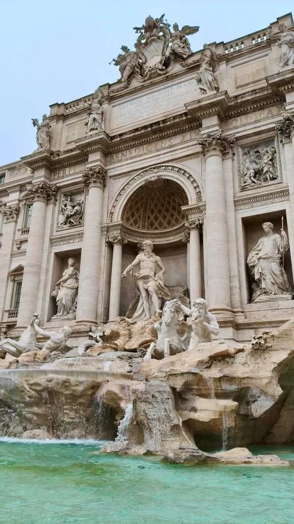 "Teraz można zrobić naprawdę ładne zdjęcia przed Fontanną di Trevi, Bez tłumów i przepychanek" - mówi Interii Aleksandra Barokowa fontanna wykonana z kamienia z licznymi rzeźbami postaci mitologicznych, kolumnami oraz ozdobnymi detalami architektonicznymi w tle, woda wypływająca do basenu na pierwszym planie.