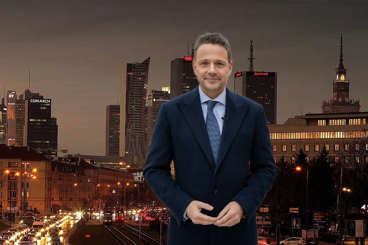 Mężczyzna w garniturze stoi na tle nocnej panoramy miasta z nowoczesnymi wieżowcami i ruchliwą ulicą, wśród których widoczny jest Pałac Kultury i Nauki.