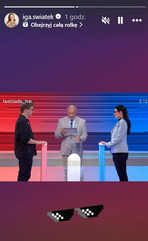 Scena z popularnego teleturnieju, w której prowadzący stoi pośrodku i trzyma kartkę, a po jego bokach znajdują się dwoje uczestników przy podświetlanych pulpitach – jeden po lewej stronie na tle czerwonego koloru, drugi po prawej na tle niebieskim. Na ...