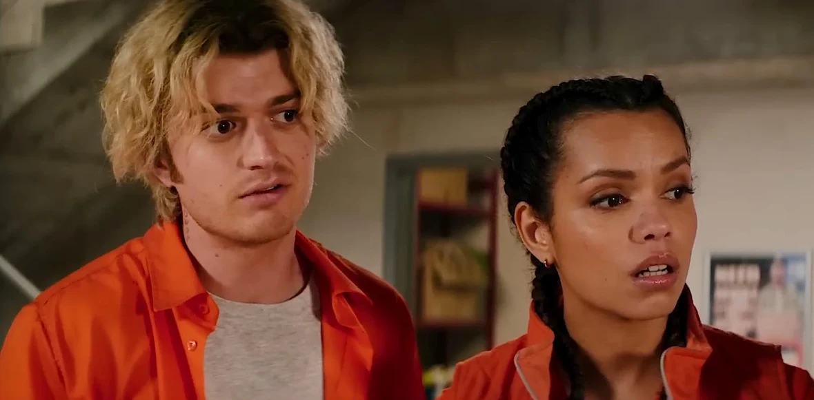 Joe Keery i Georgina Campbell w filmie "Skażenie" Dwójka młodych ludzi ubranych w pomarańczowe koszule stoi obok siebie w pomieszczeniu o surowym wystroju, oboje wyglądają na zaskoczonych lub zaniepokojonych.