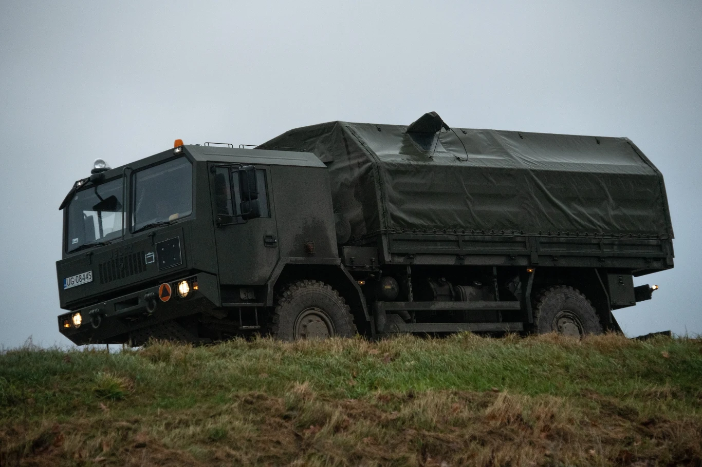 Wojsko odnotowało kolejne wloty balonów w polska przestrzeń powietrzną Wojskowa ciężarówka z plandeką, ustawiona na nachylonym terenie, z widocznymi terenowymi kołami i solidną konstrukcją kabiny. Pojazd jest pomalowany na ciemnozielony kolor maskujący, a tło stanowi pochmurne niebo.
