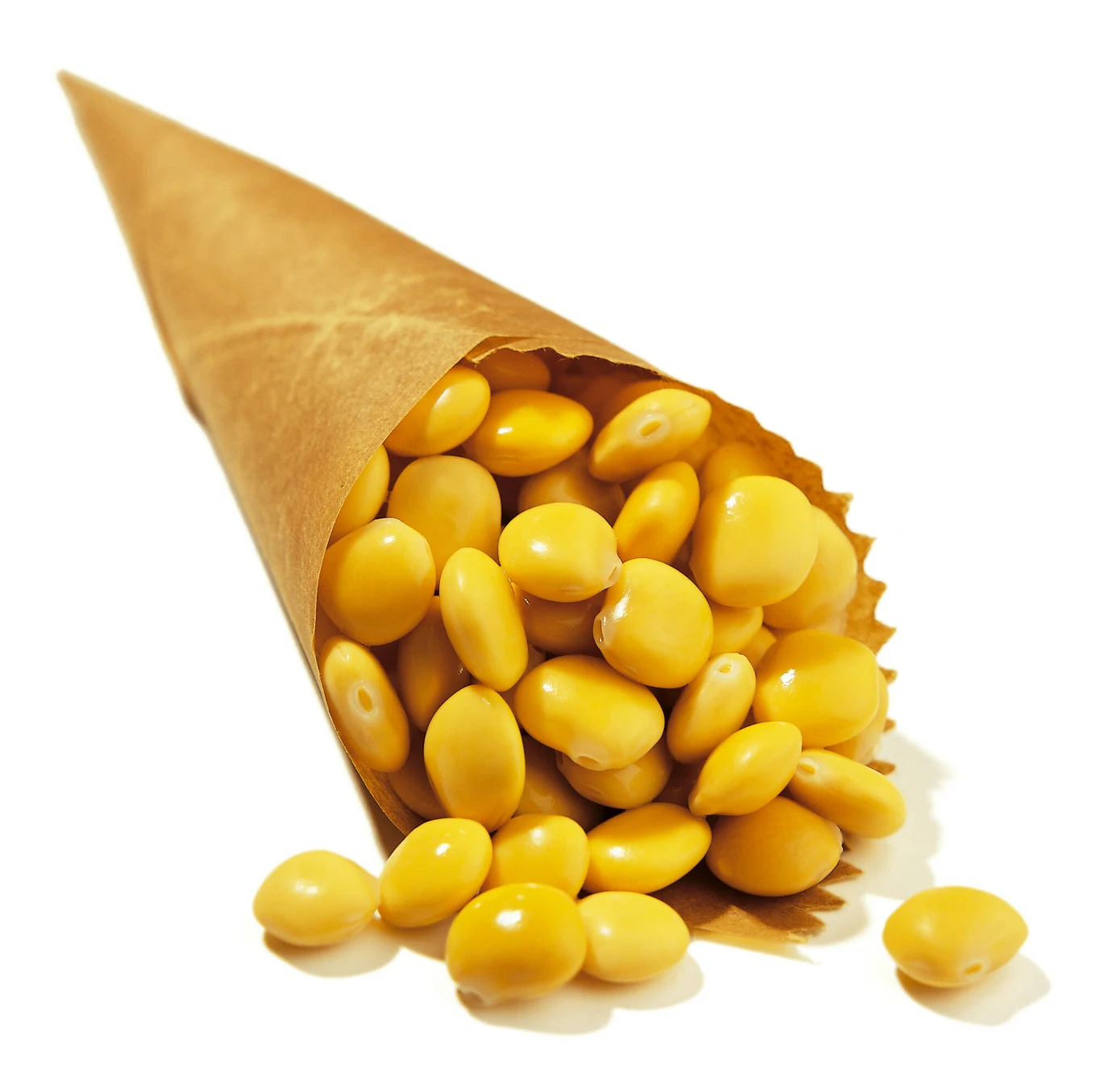 Brązowy papierowy rożek wypełniony żółtymi nasionami łubinu, które częściowo wysypują się na białą powierzchnię.