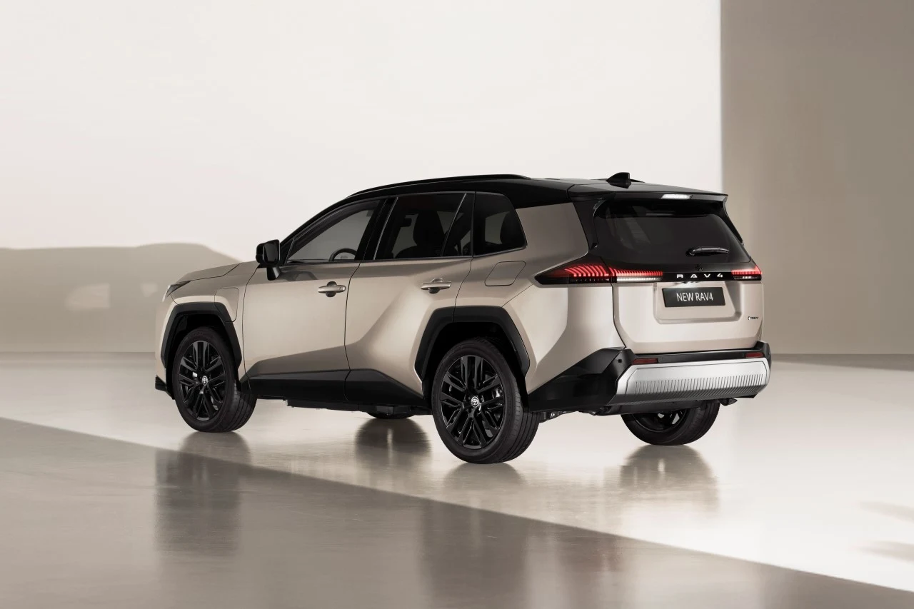 Srebrno-czarny SUV Toyota RAV4 ustawiony na jasnej podłodze w minimalistycznym wnętrzu, widok z tyłu pod kątem ukazującym nowoczesny design auta.
