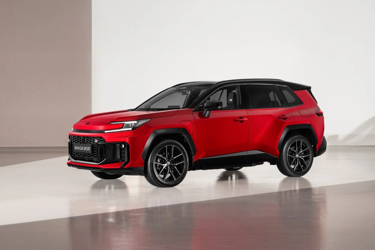 Czerwony samochód typu SUV ze sportowym, nowoczesnym designem, czarnym dachem oraz czarnymi felgami stoi na jasnej, minimalistycznej powierzchni.