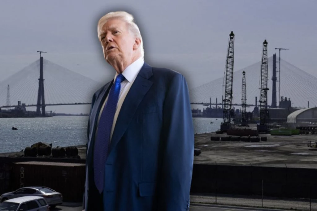 Donald Trump grozi Kanadzie w związku z budową mostu łączącego Ontario z Michigan Mężczyzna w garniturze na tle przemysłowego nabrzeża portowego z mostem i dźwigami, widoczne samochody na pierwszym planie.