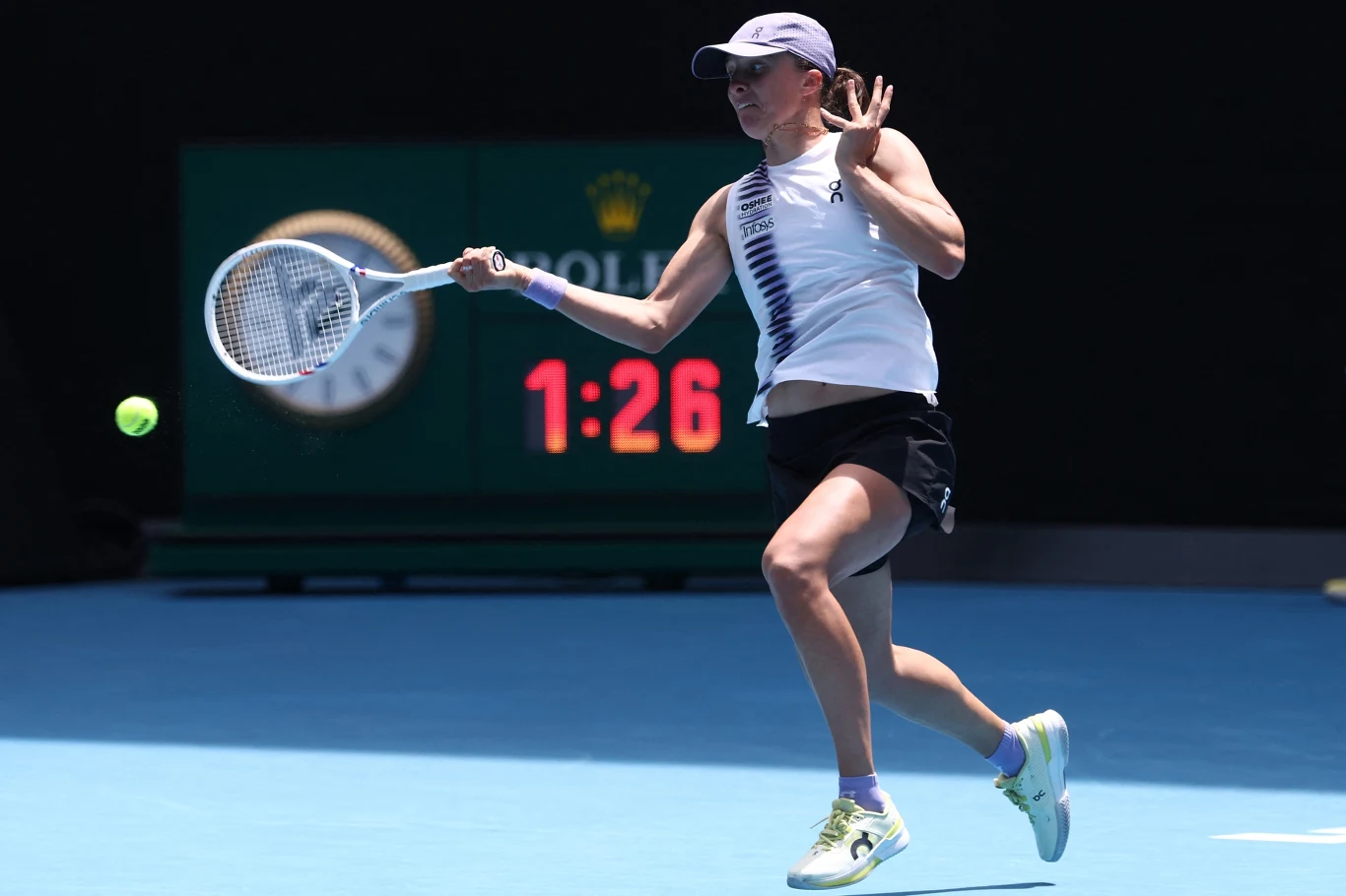 Iga Świątek w WTA Doha rozegra pierwsze mecze od Australian Open 2026 Tenisistka wykonująca dynamiczne uderzenie forehandowe na korcie, piłka tenisowa w locie, w tle zegar elektroniczny oraz elementy reklamowe.