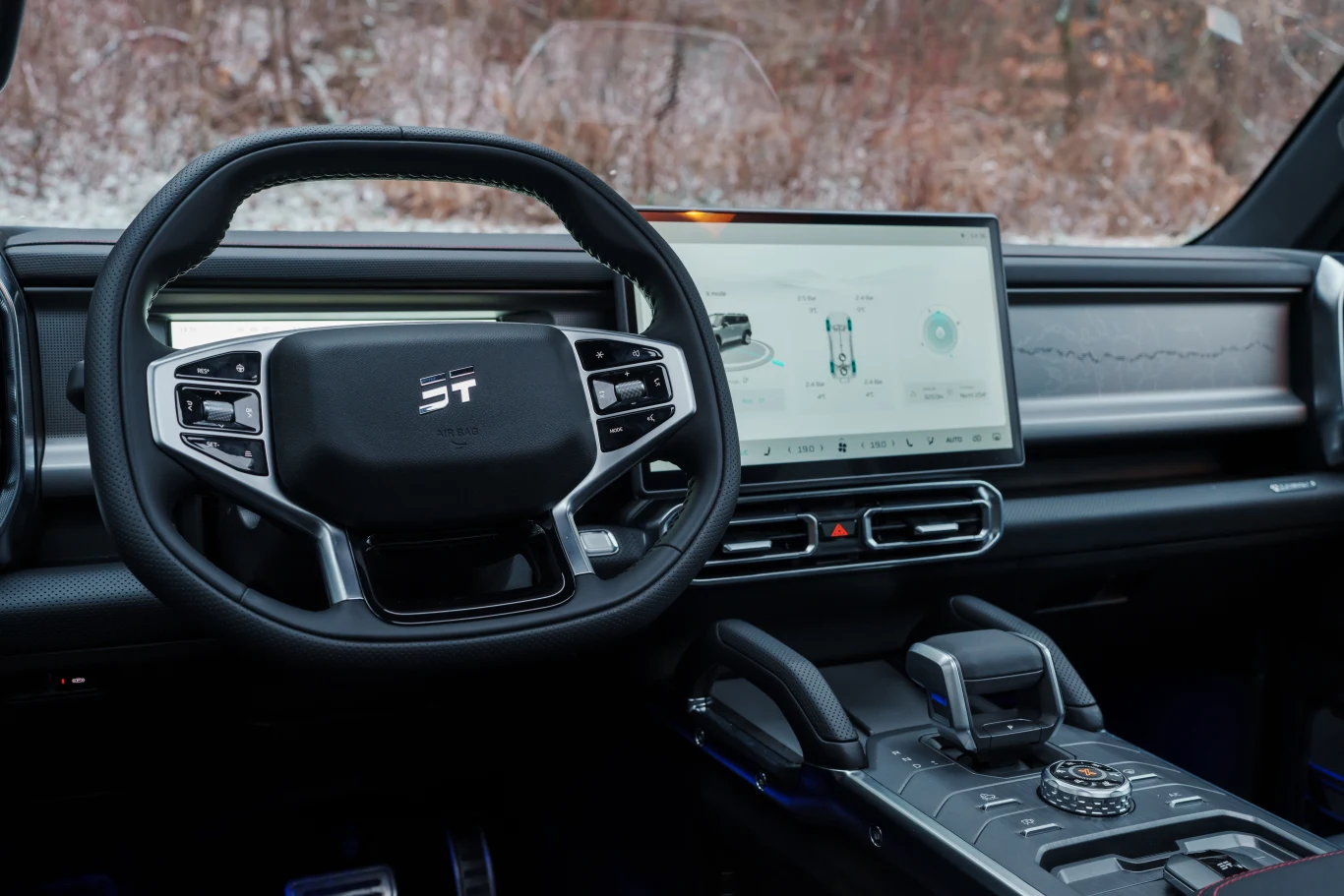 Nowoczesny kokpit samochodu z elektronicznym panelem sterowania, dużym ekranem dotykowym oraz cyfrowym zestawem wskaźników na desce rozdzielczej. Elementy wnętrza wykonane są z wysokiej jakości materiałów w ciemnych barwach, całość utrzymana w minimali...