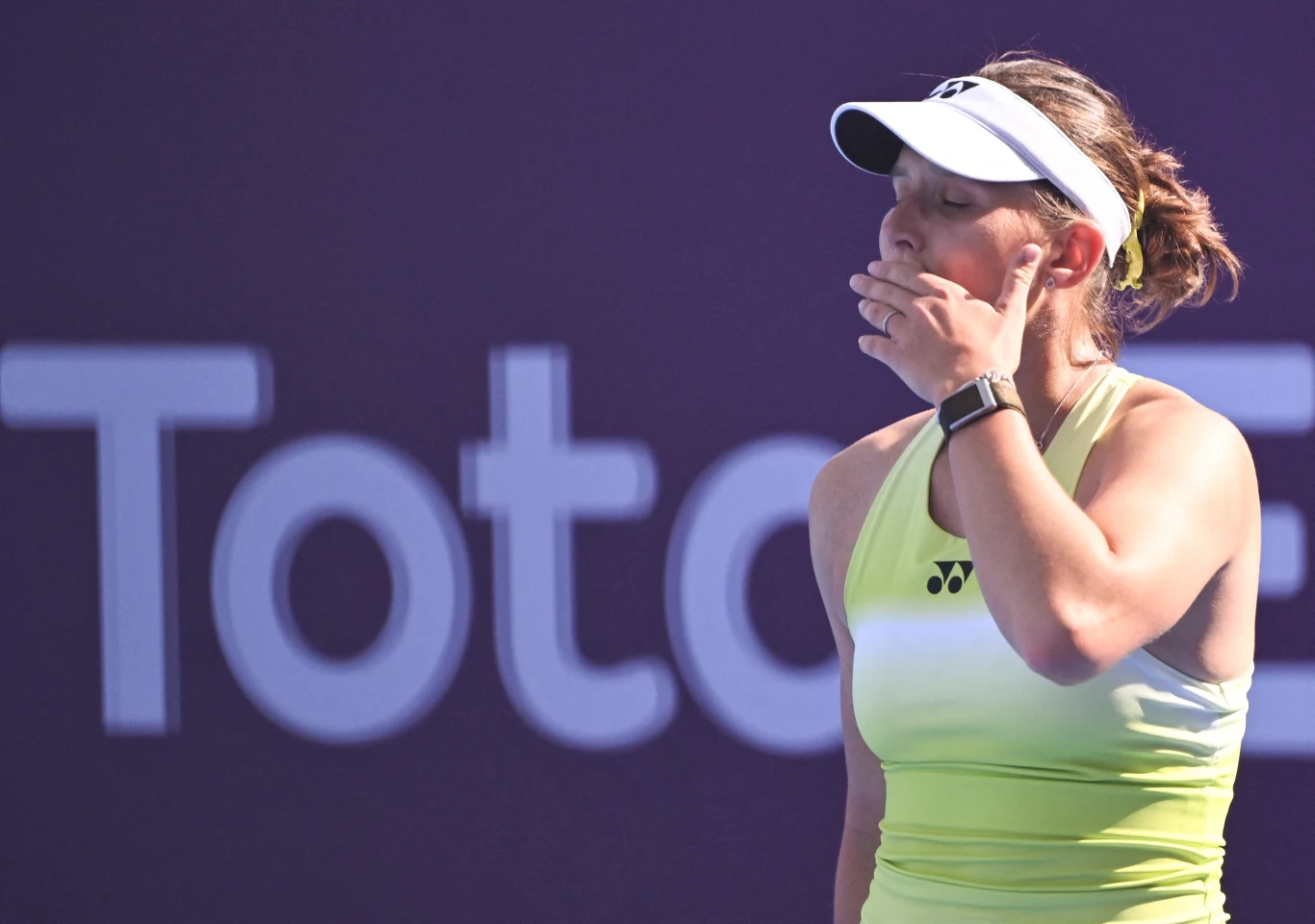 Warwara Graczowa nie wykorzystała swojej wielkiej szansy. Miała setbola w pierwszym secie Tenisistka w żółtym stroju i białej czapce zasłania ręką usta, sprawiając wrażenie zdziwionej lub rozczarowanej. W tle rozmazane logo i fioletowa tablica.