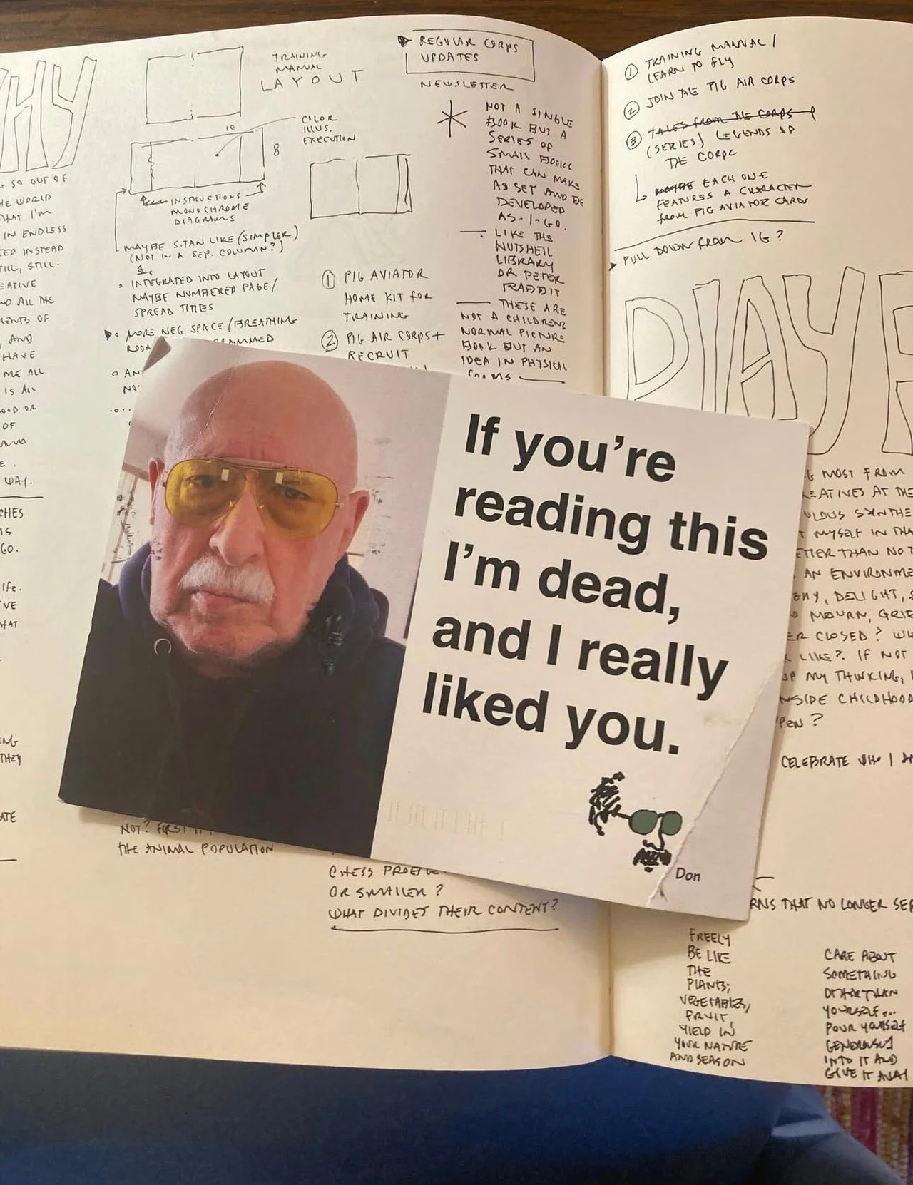 Starszy mężczyzna w żółtych okularach przeciwsłonecznych na fotografii wydrukowanej na kartce, na której widnieje napis 'If you're reading this I'm dead, and I really liked you.' Kartka leży na otwartym notesie pełnym notatek i szkiców.